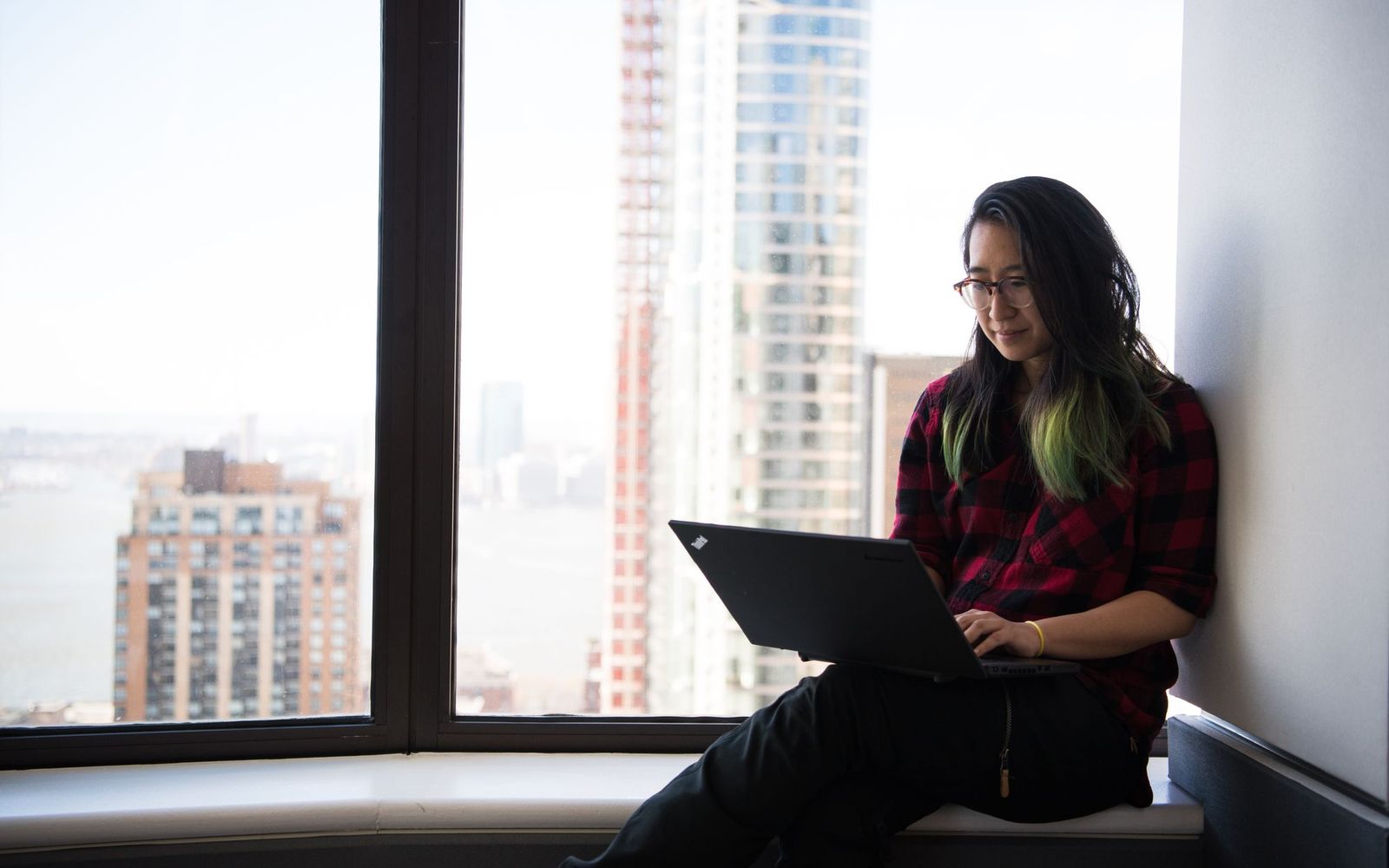 Hands typing on a laptop at a desk by a window