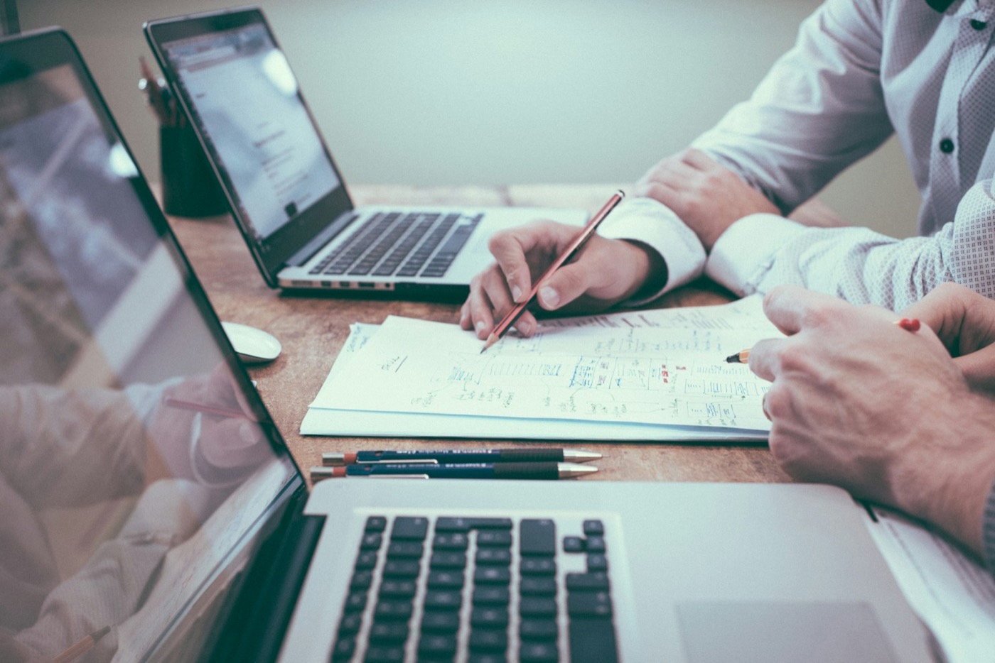 Hands reviewing paperwork beside a laptop at a desk