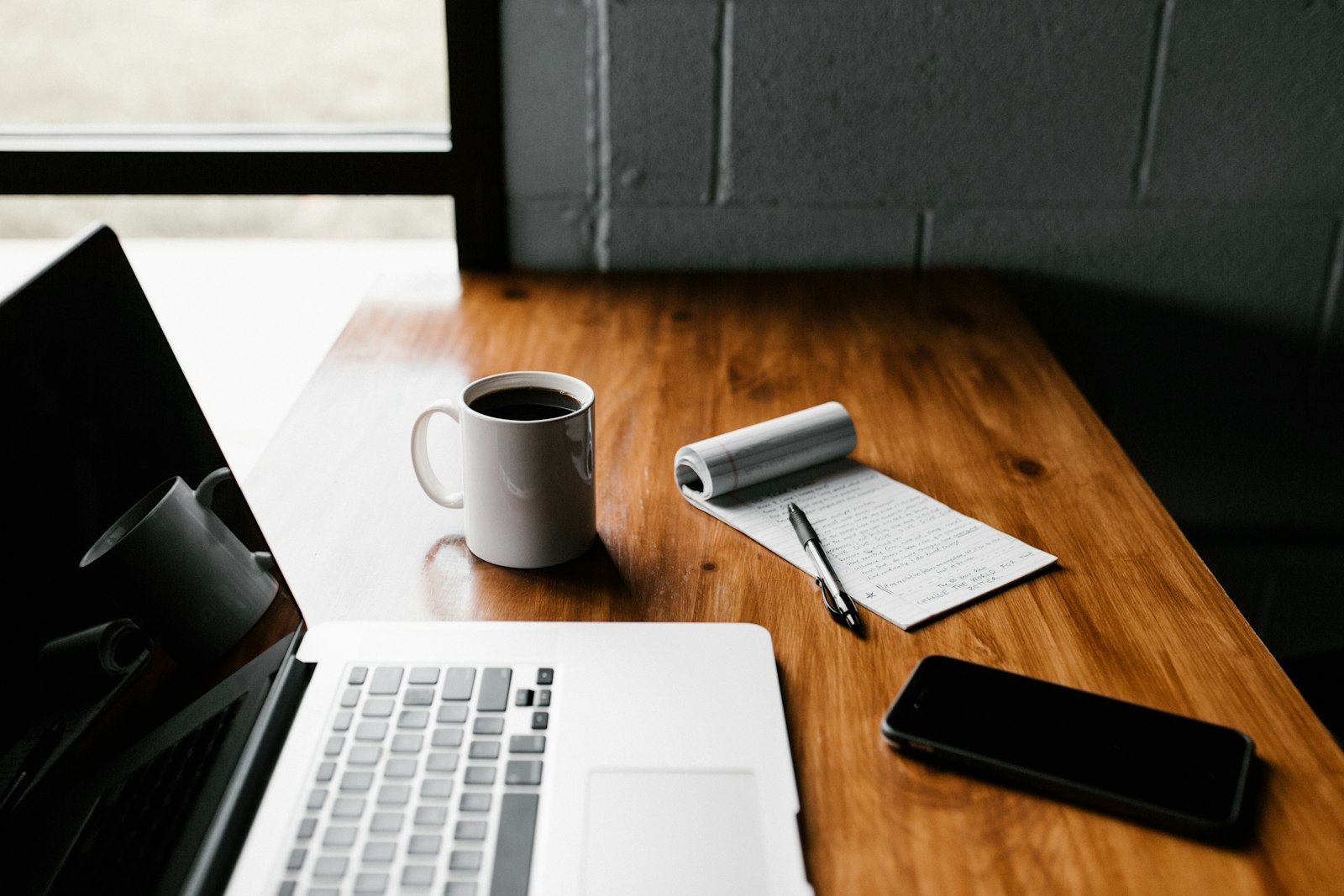 A laptop, coffee mug and phone set out on a desk