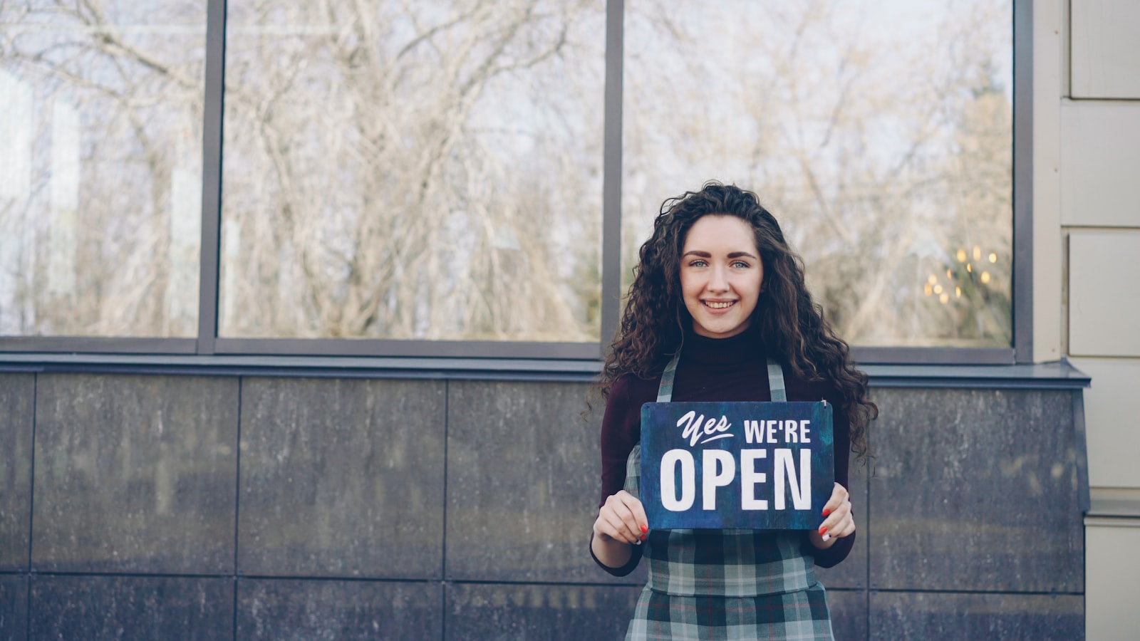 A business owner smiling while holding an open sign
